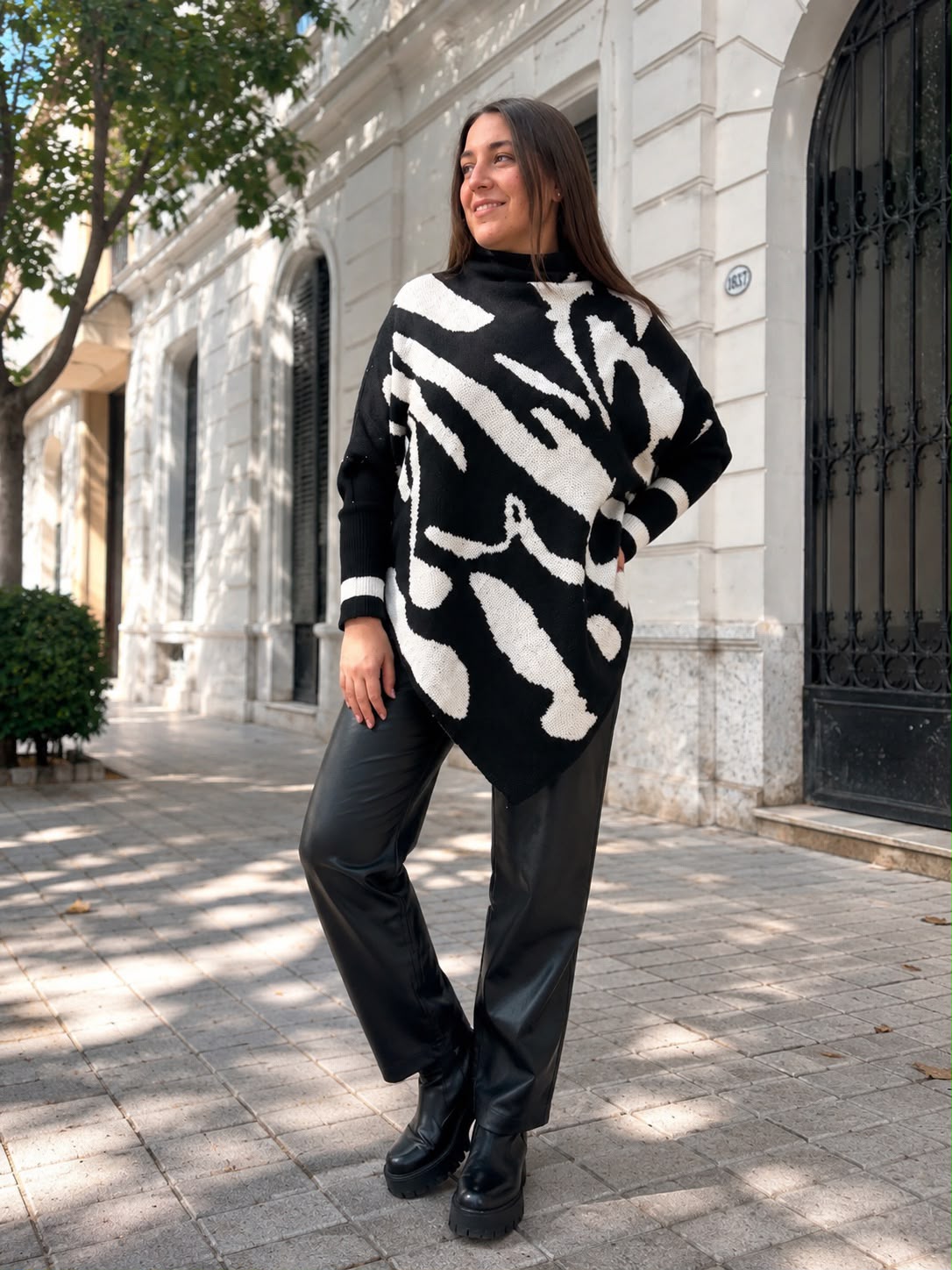 Poncho tejido negro con estampado abstracto, cuello alto y ruedo asimétrico